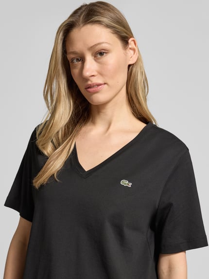 Frauenmodel trägt Relaxed Fit T-Shirt aus reiner Baumwolle von Lacoste, unifarben, V-Ausschnitt, Logo-Stitching, Nahaufnahme Oberkörper.
