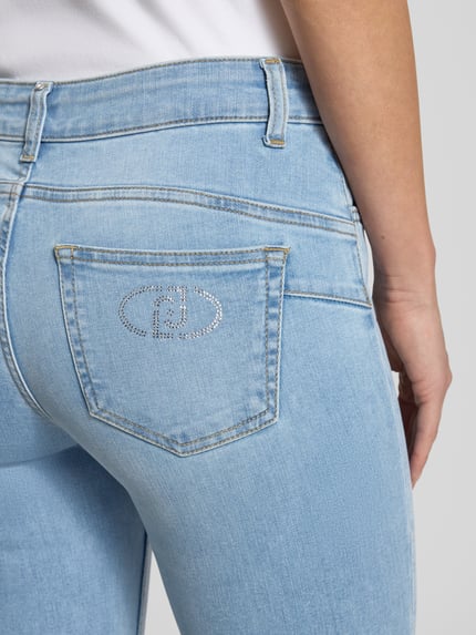 Frauenmodel trägt Jeans mit Knopfleiste Modell 'MONROE' von Liu Jo White aus Baumwoll-Mix mit Stretch-Anteil, Slim-Fit, Eingrifftaschen, Nahaufnahme Rückansicht.