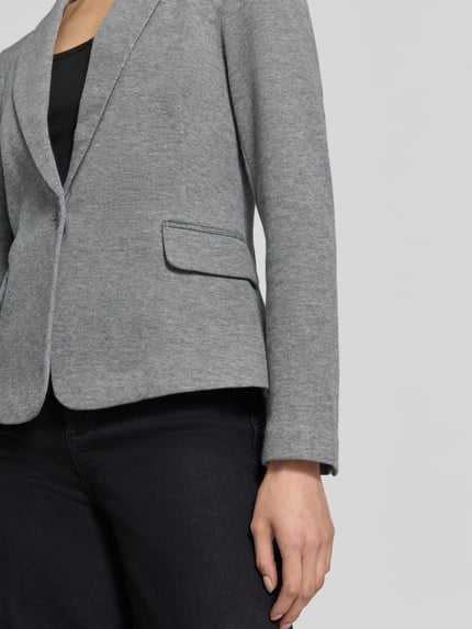 Vrouwenmodel draagt slim fit kortblazer met katoen-aandeel model 'JULIA' van VERO MODA in lichtgrijs, detailopname van het bovenlichaam.