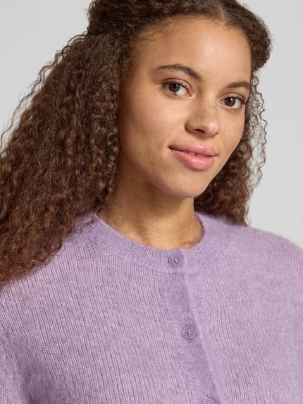 Frauenmodel trägt Cardigan aus Mohair mit Label-Schriftzug von Marc O'Polo in Flieder, Feinstrick, Struktur, Nahaufnahme Oberkörper.