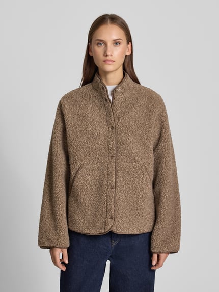 Vrouwenmodel draagt Jacke aus Teddyfell Modell 'VERA' van JJXX in bruin met rechte pasvorm, opstaande kraag, steekzakken, drukknoopsluiting, ruglengte maat S 65 cm, schouderbreedte 42 cm, borstwijdte 56 cm, mouwlengte 60 cm, teddybonttextuur, Ganzkörperansicht van voren.