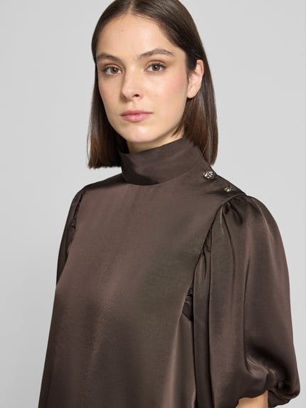 Frauenmodel trägt Regular Fit Satinbluse mit Puffärmeln Modell 'Parisa' von Neo Noir, brauner Satin, Halbarm, Stehkragen, Nahaufnahme Oberkörper.