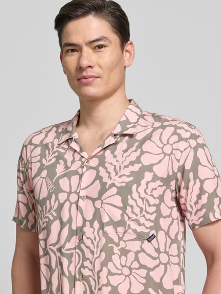 Männermodel trägt Freizeithemd im Allover-Look Modell 'Melo' von BOARDIES in Rosa und Beige mit floralem Muster, Nahaufnahme Oberkörper, Regular Fit, Reverskragen, Brusttasche, gefertigt aus reinen LENZING™ ECOVERO™ Fasern.