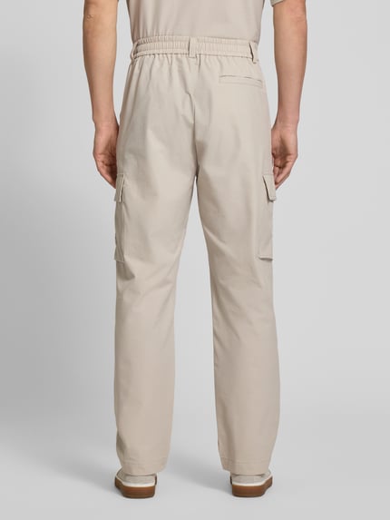 Männermodel trägt Relaxed Fit Cargohose mit Gürtelschlaufen Modell 'SRACKY' von BOSS Orange in Beige, unifarben, Ganzkörperansicht Rückansicht.