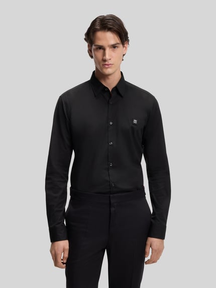 Męski model nosi Slim Fit Freizeithemd aus Baumwoll-Mix Modell 'ERMO' od HUGO, czarny, gładki materiał, krój slim fit, całkowity widok z przodu.