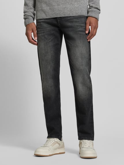 Männermodel trägt Regular Fit Straight Fit Jeans mit Label-Patch von BOSS Orange in Dark Wash Denim mit Used Look, Ganzkörperansicht von vorne.