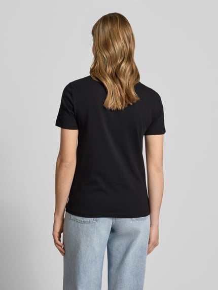 Frauenmodel trägt Damen T-Shirt aus reiner Baumwolle Modell 'KITA' von Only, Optik: Unifarben, Passform: Slim-Fit, Materialverarbeitung: Jersey, Farbe Schwarz, Kurzarm, Rundhals, Ganzkörperansicht Rückansicht.