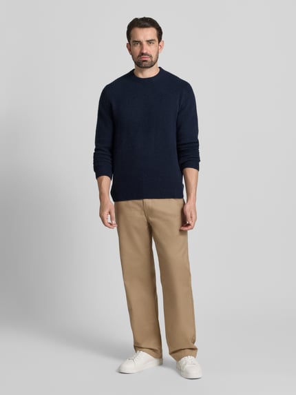 Mężczyzna nosi Sweter z dzianiny z prążkowanymi wykończeniami Model 'BLASIMON' od Jack & Jones Premium, mieszanka materiałów z dodatkiem wełny, luźny krój, okrągły dekolt, kolor granatowy, długość tyłu 64 cm, długość rękawów 69 cm, Ganzkörperansicht von vorne.