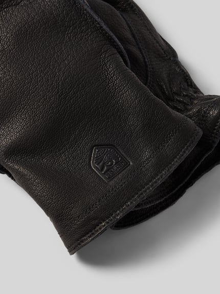 Productfoto, handschoenen van echt leer model 'Jon' van Hestra in zwart met zichtbaar labeldetail, fijne structuur, heren handschoenen.