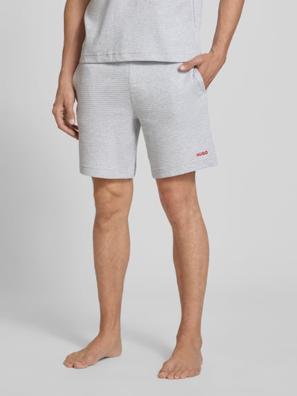 Männermodel trägt Regular Fit Sweatshorts aus Baumwoll-Mix Modell 'AUSTIN' von HUGO, hellgrau mit feiner Struktur, Nahaufnahme Oberschenkel, Herren Sweatshorts von HUGO.