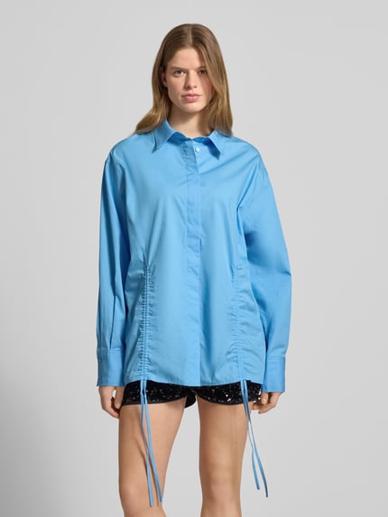 Frauenmodel trägt Oversized Bluse mit Kordelzug und verdeckter Knopfleiste von Karo Kauer, Reine Baumwolle, Oversized-Fit, Hemdblusenkragen, Sportmanschetten, Bund mit Kordelzug, Label-Patch, Rückenlänge 75 cm, Ärmellänge 61 cm, Himmelblau mit glatter Textur, Ganzkörperansicht von vorne.