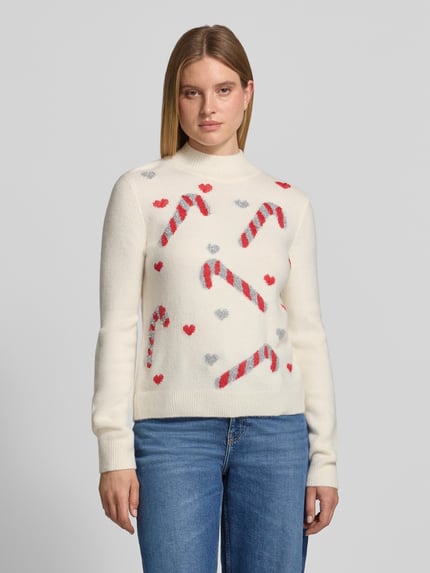 Frauenmodel trägt Strickpullover im Allover-Look mit Stehkragen von Christian Berg Woman, cremefarben mit roten und grauen Mustern, Material-Mix mit Stretch-Anteil, Slim Fit, Ganzkörperansicht von vorne.