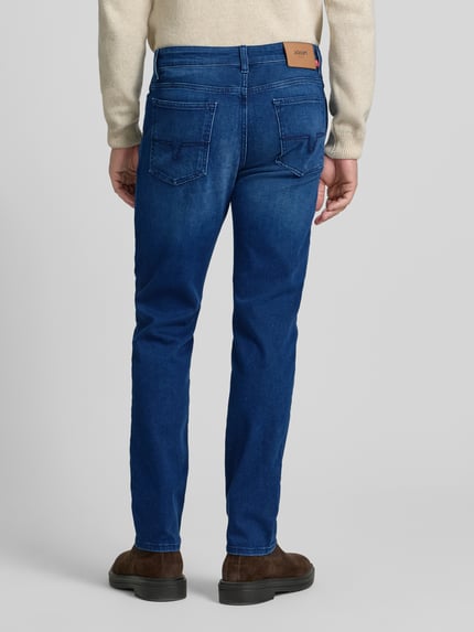 Mężczyznamodel nosi Jeans mit 5-Pocket-Design Modell 'Mitch' od JOOP! Jeans, prosta nogawka, elastyczna bawełna, widok całej sylwetki od tyłu.