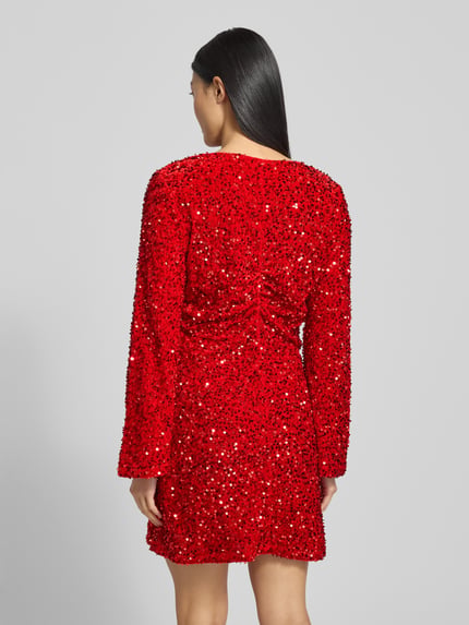 Frauenmodel trägt Minikleid mit Pailletten Modell 'BARINA' von Vila in leuchtendem Rot, A-Linie, strukturierte Oberfläche, Ganzkörperansicht Rückansicht.