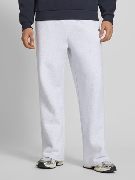 Mannenmodel draagt Straight Leg Sweatpants met elastische band van KARL KANI, katoenmix, achterzak, binnenbeenlengte maat M 39 cm. Ganzkörperansicht von voren.
