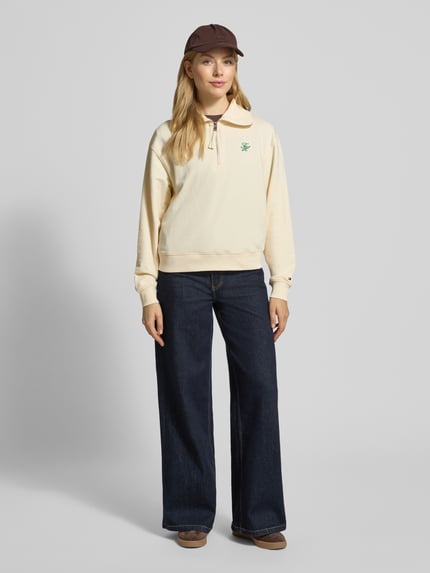 Vrouwenmodel draagt Regular Fit Sweatshirt aus Baumwoll-Mix van Tommy Hilfiger in uni crème, lange mouwen, Troyer kraag, Ganzkörperaanzicht van voren.