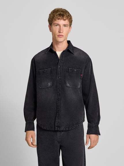 Mężczyznamodel nosi Regular Fit Jeanshemd aus reiner Baumwolle od Replay, czarna koszula jeansowa, krój regular fit, kołnierzyk typu kent, kieszenie na piersi, z długim rękawem, listwa guzikowa, tekstura gładka, widoczna lekka struktura materiału, przód z przodu, kontekst: koszula jeansowa od Replay z bawełny, długość tyłu w rozmiarze M: 72 cm, szerokość ramion w rozmiarze M: 46 cm, szerokość klatki piersiowej w rozmiarze M: 53 cm, długość rękawów w rozmiarze M: 58 cm, pełna długość, widok z przodu.