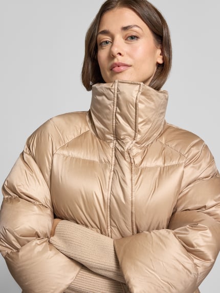 Frauenmodel trägt Steppjacke mit Kunstfell Modell 'Mila' von ROCKANDBLUE, Wypełnienie puchem i pierzem, krój regular fit, kołnierz ze sztucznego futra, zamek błyskawiczny kryty, kieszenie zapinane na zamek błyskawiczny, Długość tyłu w rozmiarze 36: 61 cm, Szerokość ramion w rozmiarze 36: 43 cm, Szerokość w rozmiarze 36: 58 cm, Długość rękawów w rozmiarze 36: 46 cm, kolor beżowy, pikowana tekstura, Nahaufnahme Oberkörper.