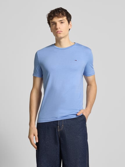 Männermodel trägt Regular Fit T-Shirt aus Baumwoll-Mix von Tommy Jeans, Optik: Unifarben, Logo-Stitching, Ganzkörperansicht von vorne.