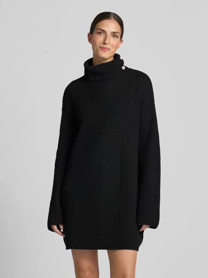 Frauenmodel trägt Strickkleid mit Rollkragen von Liu Jo White in Schwarz, grobe Maserung, Knöpfe, gerader Schnitt, Ganzkörperansicht von vorne. Material-Mix mit Woll-Anteil, Minikleid, Rückenlänge 88 cm, Brustweite 52 cm, Ärmellänge 54 cm.