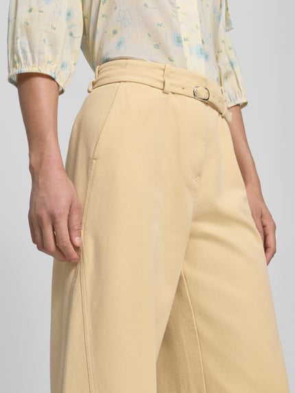 Frauenmodel trägt Stoffhose mit Gürtel und Eingrifftaschen von JAKE*S STUDIO WOMAN, Reine Baumwolle, ausgestellter Schnitt, Nahaufnahme Oberkörper.