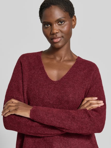 Frauenmodel trägt Strickpullover aus Woll-Mix mit V-Ausschnitt Modell 'THORA' von MOS MOSH in Bordeaux, Nahaufnahme Oberkörper, Regular Fit, feine Textur, Alpaka-Anteil, Damen Strickpullover, Rückenlänge 82 cm, Ärmellänge 46 cm.