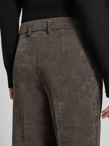 Frauenmodel trägt Regular Fit Cordhose mit Bundfalten Femke 2-800 von Stehmann, braune Struktur-Optik, Detailaufnahme Rückenbereich.