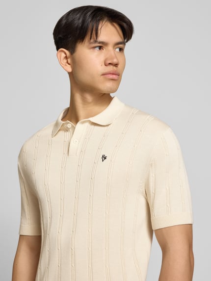 Männermodel trägt Slim Fit Strick-Poloshirt mit Label-Stitching von REVIEW, Reine Baumwolle, Zopfmuster, Knopfleiste, Nahaufnahme Oberkörper.