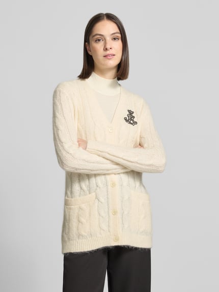 Frauenmodel trägt Cardigan aus Mohair mit Logo-Applikation von LAUREN RALPH LAUREN in Creme mit Zopfmuster, Strickoptik, Ganzkörperansicht von vorne.