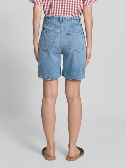 Vrouwenmodel draagt Regular Fit Bermudas uit mix van katoen en lyocell model 'VILLA' van Vero Moda met denimlook, 5-pocketmodel, lichte blauwe kleur, zichtbare riemlussen en boord met tunnelkoord. Ganzkörperansicht Rückansicht.