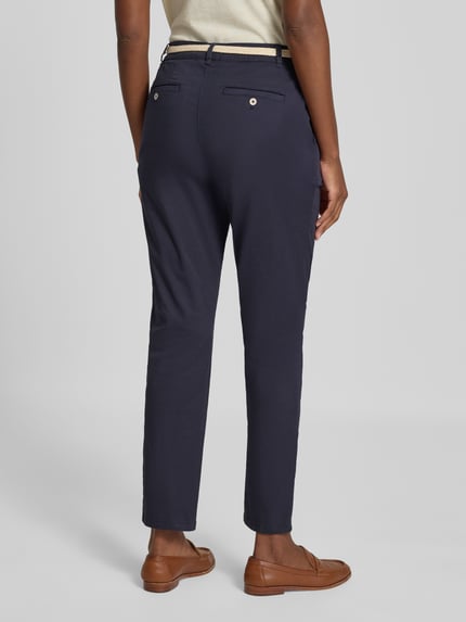 Männermodel trägt chinosy 'Chino mit Gürtel und Gesäßtaschen' von Christian Berg Woman, mieszanka bawełny i elastanu, krój regular fit, kieszenie z tyłu, pasek, szerokość w rozmiarze 36: 41 cm, długość wewnętrzna nogawki w rozmiarze 36: 74 cm, Ganzkörperansicht Rückansicht