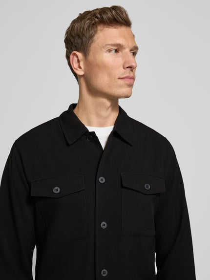Männermodel draagt Hemdjacke met knoopsluiting van Lindbergh, zwart, regular fit, borstzakken, viscosemix, detailopname bovenlichaam.