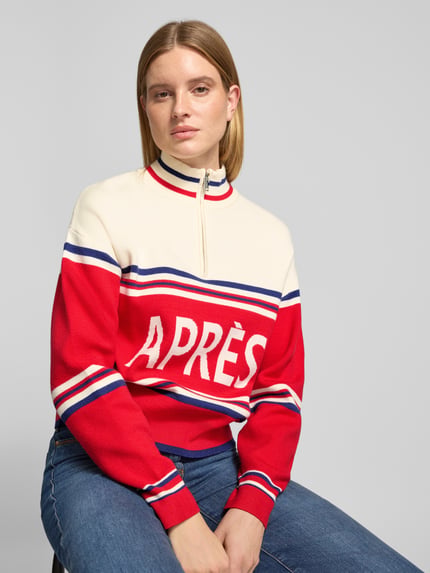 Frauenmodel trägt Troyer mit Après-Schriftzug von JAKE*S WOMAN CASUAL, mehrfarbig, gestreift, Strickoptik, Nahaufnahme Oberkörper.