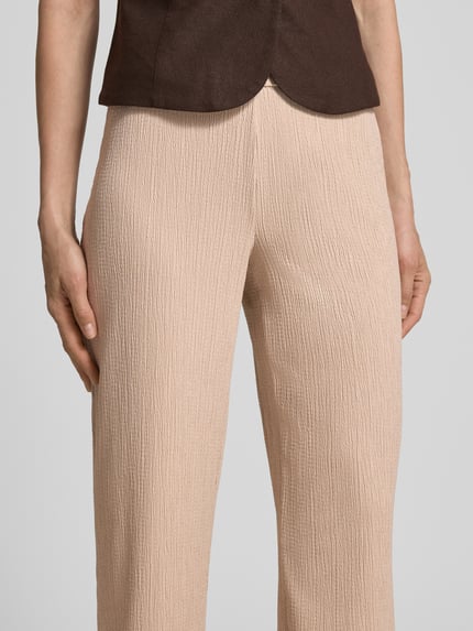 Frauenmodel trägt Stoffhose mit elastischem Bund Modell 'Filiz' von STEHMANN, Relaxed-Fit, Strukturmuster, Nahaufnahme Oberkörper.