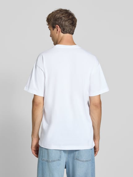Männermodel trägt Regular Fit T-Shirt aus reiner Baumwolle Modell 'Column' von Carhartt Work In Progress, weiß, glatte Textur, Ganzkörperansicht Rückansicht. Herren T-Shirt, Rundhalsausschnitt, Label-Print, Rückenlänge bei Größe M: 75 cm.