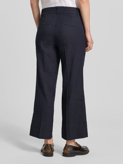 Frauenmodel trägt dunkelblaue Chino aus Leinen-Mix mit Bügelfalte Modell 'CALIFORNIA' von Cambio, Ganzkörperansicht Rückansicht, French Pockets, Straight Fit, Baumwoll-Anteil.