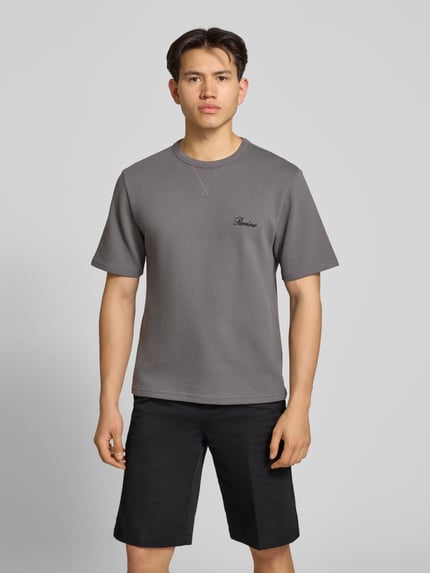 Männermodel trägt T-Shirt mit Label-Stitching von REVIEW, grauer Baumwoll-Mix, Waffelstruktur, gerader Schnitt, Nahaufnahme Oberkörper.