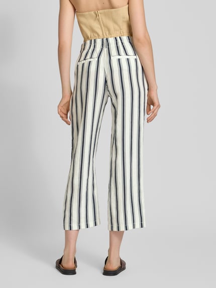 Vrouwenmodel draagt Straight Fit Leinenhose in verkürzter Passform van Christian Berg Woman, wit met blauwe strepen, zuiver linnen, straight fit, verkort model, knoop- en ritssluiting, bandwijdte maat 36: 39 cm, binnenbeenlengte maat 36: 66 cm, geheel zicht van achteren.