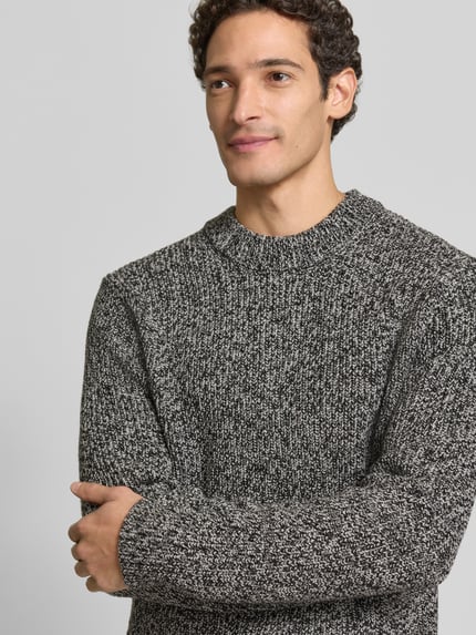 Männermodel trägt Pullover Modell 'Suolaa' mit Rippabschlüssen von HUGO, melierte Strickoptik, Strukturmuster, Rundhals, Nahaufnahme Oberkörper.