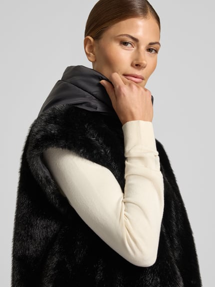 Frauenmodel trägt Regular Fit Jacke aus Kunstfell Modell 'JUNIPER' von Blauer USA in Schwarz mit Stehkragen, Nahaufnahme Oberkörper.