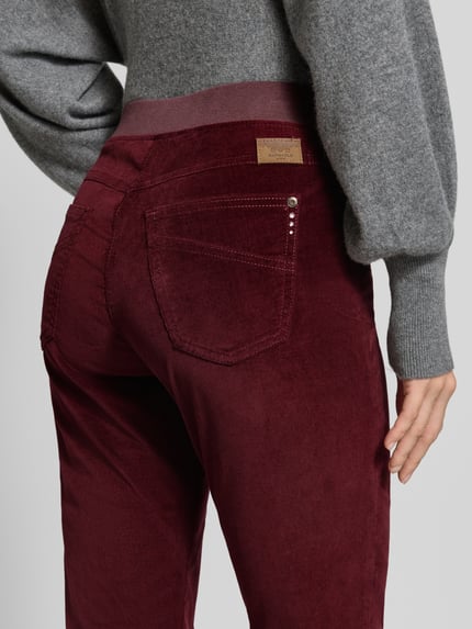 Kobieta nosi bordowe jeansy Slim Fit Jeans aus Baumwoll-Viskose-Mix Modell 'Pamina' od Raphaela By Brax, tekstura welurowa, zbliżenie tylnej części, damskie straight fit jeans od Raphaela By Brax.