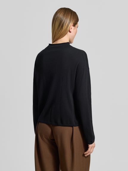 Frauenmodel trägt Turtleneck mit Mock Neck von MARC O'POLO in Schwarz, Strukturstrick, Relaxed Fit, lange Ärmel, Ganzkörperansicht Rückansicht.