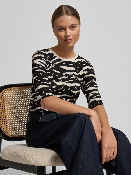 Vrouwenmodel draagt T-Shirt met 3/4-Arm van Marc Cain, zwart-wit print, getailleerd, ronde hals, katoen-elastaanmix. Nahaufnahme Oberkörper.