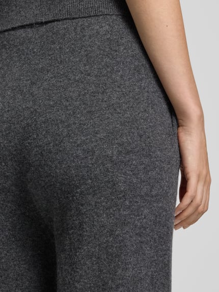 Frauenmodel trägt Hose aus Lanawoll-Mix mit Kaschmir-Anteil Modell 'LOTTIMO' von MM by Max Mara, meliertes Dunkelgrau, weiche Textur, Nahaufnahme Hüfte, Straight Fit, elastischer Bund, KI-modifiziertes Bild.