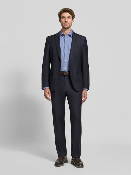 Männermodel trägt Comfort Fit Businesshemd aus reiner Baumwolle von OLYMP in Blau, kombiniert mit dunklem Anzug, Ganzkörperansicht von vorne, Herren Businesshemd von OLYMP Luxor.