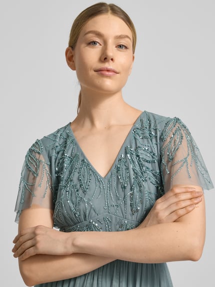 Kobiece modelka nosi sukienka wieczorowa 'Abendkleid mit Ziersteinbesatz' od Christian Berg Cocktail, linia a, dekolt w serek, marszczenia, obszycie ozdobnymi kamieniami, zamek błyskawiczny z tyłu, długa sukienka, długość tyłu w rozmiarze 36: 140 cm, szerokość w rozmiarze 36: 38 cm, długość rękawów w rozmiarze 36: 21 cm, niebiesko-zielone odcienie, geometryczne wzory, tekstura tiulu, detaliczne zdobienia, zbliżenie na górną część ciała, przód