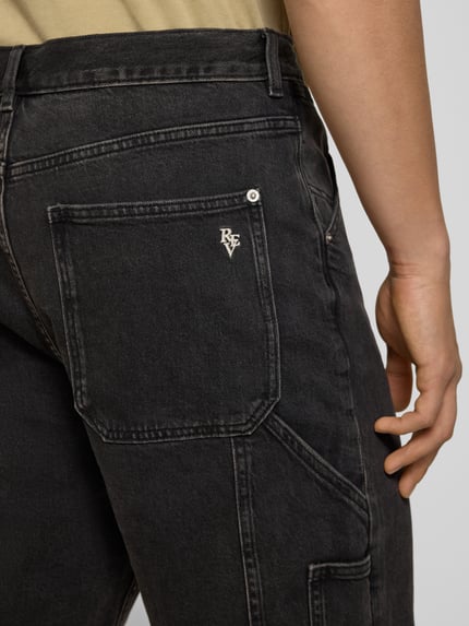 Männermodel trägt Bermudas mit seitlichen Eingrifftaschen und Gesäßtaschen von REVIEW aus Baumwoll-Mix mit Stretch-Anteil in dunklem Farbton, Detailaufnahme Gesäßtasche.
