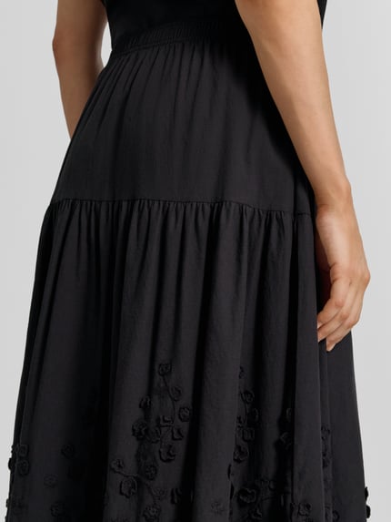 Kobiece model prezentuje spódnica midi z haftami model 'FAHIMA' od Soyaconcept, czarna bawełna, linia a, elastyczny pas, haftowana faktura, całkowita długość 83 cm, szerokość w rozmiarze S: 36 cm, zbliżenie na dolną część ciała