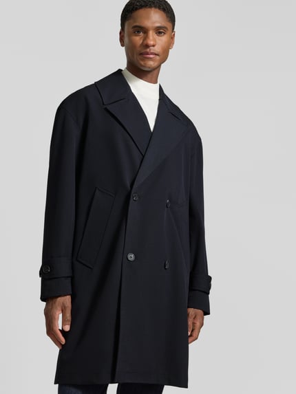 Männermodel trägt Trenchcoat mit doppelreihiger Knopfleiste von Antony Morato in Dunkelblau, glatte Struktur, Nahaufnahme Oberkörper. Material-Mix mit Viskose-Anteil, Straight Fit, Reverskragen, seitliche Eingrifftaschen, Ärmelriegel mit Knopf, Rückenlänge 100 cm, Schulterbreite 48 cm, Brustweite 57 cm, Ärmellänge 59 cm.