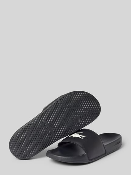 Produktfoto, Badeschuhe mit Logo Print Modell 'SERVE SLIDE' von Lacoste, czarne, jednokolorowe, zaokrąglony nosek, płaski obcas, teksturowana podeszwa, fason wsuwany, logo z przodu